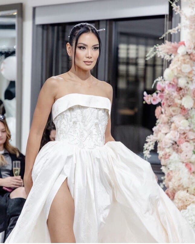 Bride among blossoms with sleek bun and polished bridal makeup